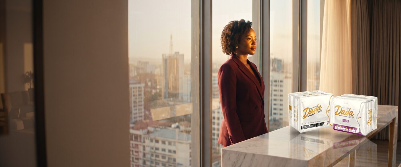 Kenyan woman in a merlot blazer at a Nairobi window with Dadacare Plus pads